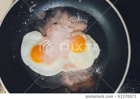 Appetizing photograph of scrambled eggs from one chicken egg in a pan with boiling sunflower oil. 61570071