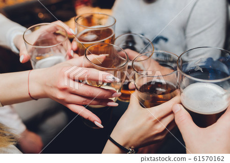 Close up shot of group of people clinking glasses with wine or champagne in front of bokeh background. older people hands. Close up shot of group of people clinking glasses with wine or champagne in front of bokeh background. older people hands. 61570162