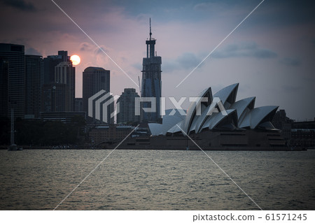 Setting sun behind Sydney skyline in New South Wales 61571245