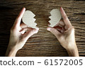 woman hand holding broken heart paper cut on wooden background 61572005