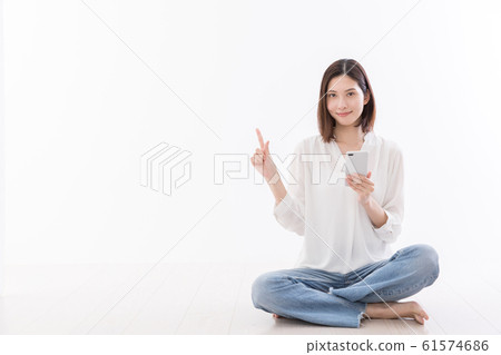 年輕女子坐在地板智能手機手指 61574686