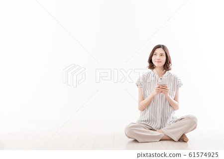年輕女子坐在地板座位的智能手機 61574925