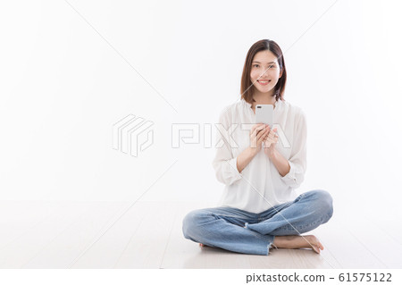 年輕女子坐在地板座位的智能手機 61575122