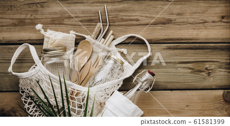 Mesh market bag with bamboo cutlery, reusable bottles and eco cotton bags on wooden background Mesh market bag with bamboo cutlery, reusable bottles and eco cotton bags on wooden background 61581399