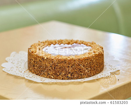 Delicious biscuit cake with nuts on a lace napkin. Delicious biscuit cake with nuts on a lace napkin. 61583203