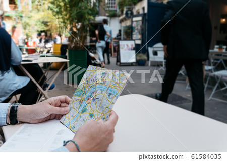 Woman tourist holds a map of the city in a trendy shopping area sitting on a terrace Woman tourist holds a map of the city in a trendy shopping area sitting on a terrace 61584035