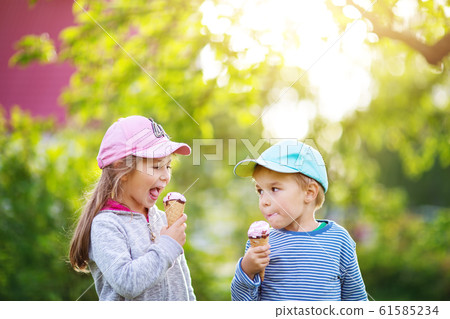 Happy child eating ice cream outdoors in summer Happy child eating ice cream outdoors in summer 61585234