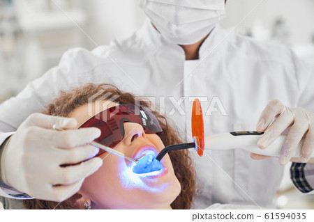 Attractive lady doing whitening procedure in dental clinic 61594035