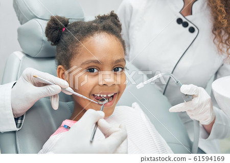 Happy afro kid on regular check up of teeth in dental clinic 61594169