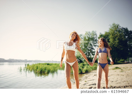 Sporty mother with cute daughter walking near lake Sporty mother with cute daughter walking near lake 61594667