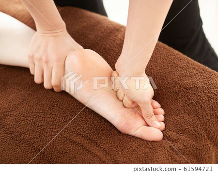 Woman receiving a relaxation massage on the soles in a bright shop Woman receiving a relaxation massage on the soles in a bright shop 61594721