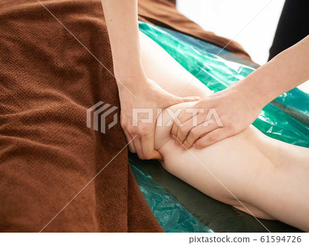 女人在明亮的店裡接受大腿按摩 61594726