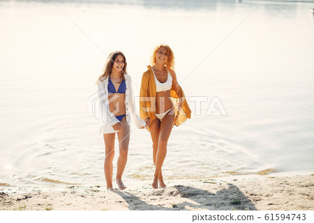 Sporty mother with cute daughter walking near lake 61594743