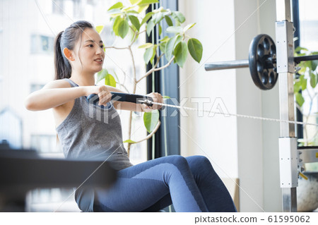 Woman training on rowing machine 61595062