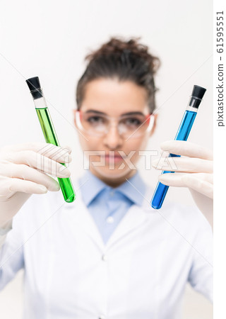 Gloved hands of female clinician or pharmacist showing flasks with vaccine Gloved hands of female clinician or pharmacist showing flasks with vaccine 61595551