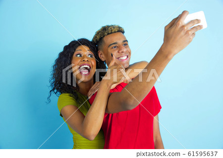 Young emotional african-american man and woman on blue background Young emotional african-american man and woman on blue background 61595637