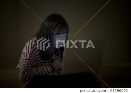 A child watching a computer at night 61596673