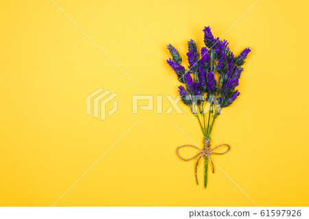 one twig of a lavender flower tied up with a thread and bow on a yellow background. copy space for design ideas one twig of a lavender flower tied up with a thread and bow on a yellow background. copy space for design ideas 61597926