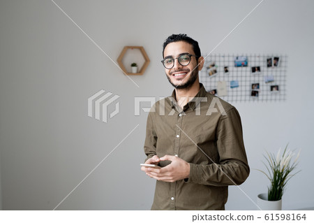 Young businessman with toothy smile using smartphone in front of camera 61598164
