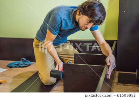 Frustrated Man Putting Together Self Assembly Furniture Frustrated Man Putting Together Self Assembly Furniture 61599952