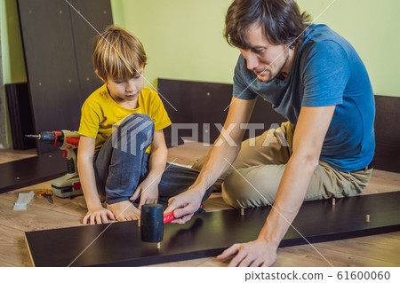 Father and son assembling furniture. Boy helping his dad at home. Happy Family concept 61600060