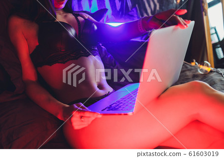 Beautiful, young girl posing in front of a web camera, working as a model. The concept of online flirting. Beautiful, young girl posing in front of a web camera, working as a model. The concept of online flirting. 61603019
