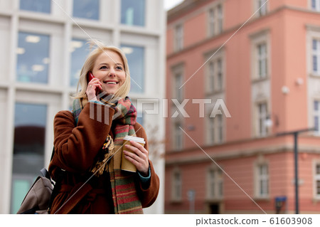 woman with cup of coffee talking by mobile phone woman with cup of coffee talking by mobile phone 61603908