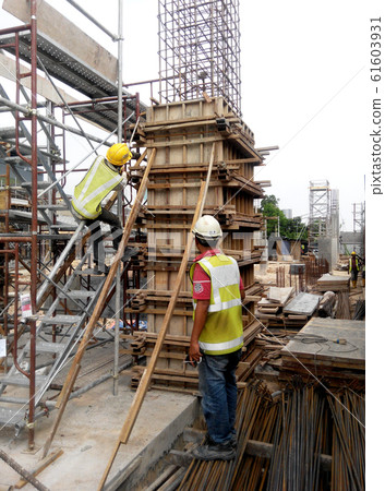 Construction workers fabricating column timber form work and reinforcement bar at the construction site in Malacca, Malaysia.  61603931
