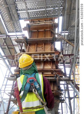 Construction workers fabricating column timber form work and reinforcement bar at the construction site in Malacca, Malaysia.  61603939