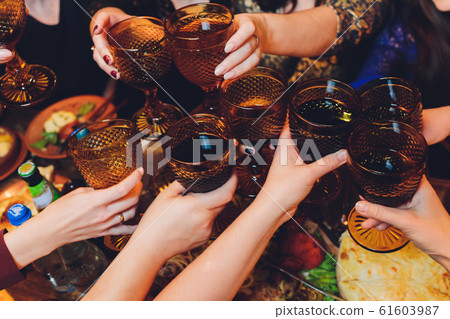 Close up shot of group of people clinking glasses with wine or champagne in front of bokeh background. older people hands. Close up shot of group of people clinking glasses with wine or champagne in front of bokeh background. older people hands. 61603987