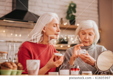 Two good-looking elderly women applying new cream 61605997