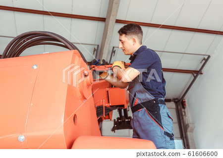 Technician doing some maintenance work on farm machine 61606600