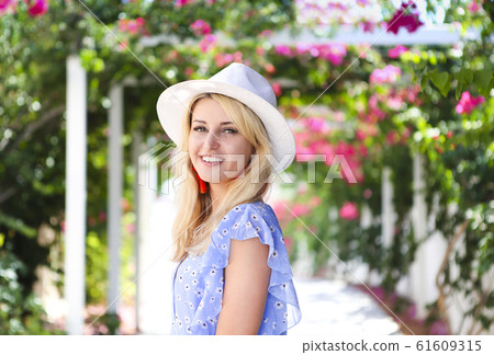 Blond girl in straw hat in front of pink 61609315
