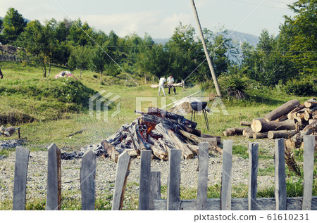 Fire in backyard and man out of focus preparing lamb meat for cooking on a spit 61610231