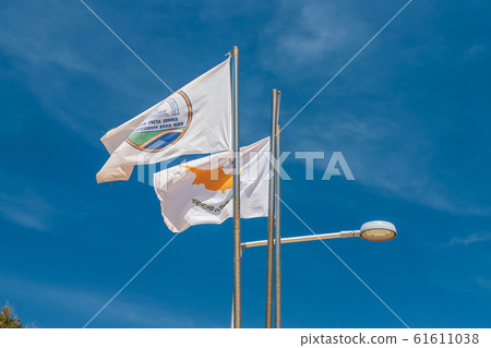 The flag of Agia Napa municipality and the flag of Cyprus. Flags on the flagpole and the stereet lamp post. The wind inflates the flag. The flag of Agia Napa municipality and the flag of Cyprus. Flags on the flagpole and the stereet lamp post. The wind inflates the flag. 61611038