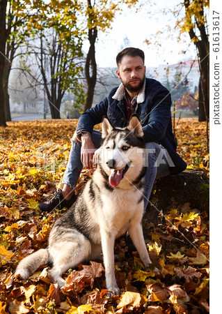 Hipster stylish guy with his husky dog in autumn Hipster stylish guy with his husky dog in autumn 61613617