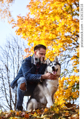 Hipster stylish guy hug his husky dog in autumn Hipster stylish guy hug his husky dog in autumn 61613618