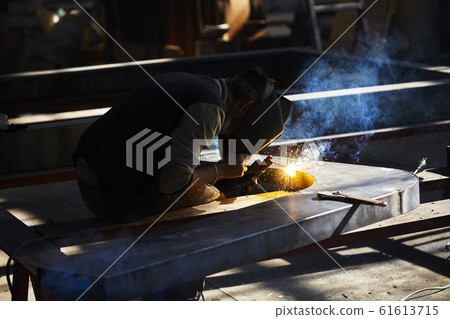 welder working with electrode at semi-automatic arc welding in manufacture production plant.Selective focus welder working with electrode at semi-automatic arc welding in manufacture production plant.Selective focus 61613715