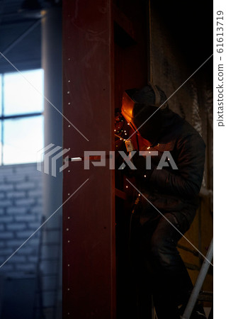 welder working with electrode at semi-automatic arc welding in manufacture production plant.Selective focus 61613719