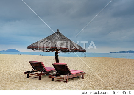 Two loungers under straw parasol at the beach  61614568