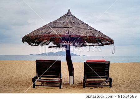 Two loungers under straw parasol at the beach  61614569