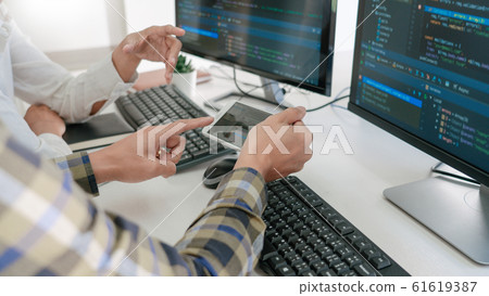 Young startup Programmers Sitting At Desks Working Young startup Programmers Sitting At Desks Working 61619387