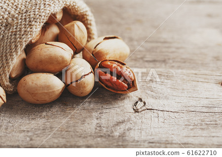 Pecans spill out of a bag on a wooden table, Pecans spill out of a bag on a wooden table, 61622710
