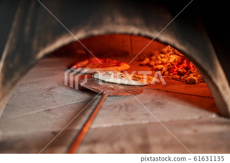 Baked tasty margherita pizza in Traditional wood oven in Naples restaurant, Italy. Original neapolitan pizza. Red hot coal. 61631135