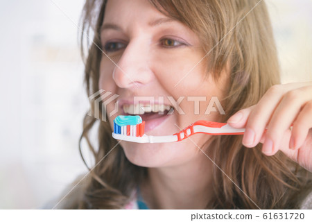 Smiling woman holding toothbrush Smiling woman holding toothbrush 61631720