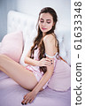 Beautiful young woman sensually sitting on the bed in pink pajama set 61633348