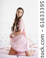 Beautiful young woman smiling sensually on the bed playing with her pink pajama set 61633395