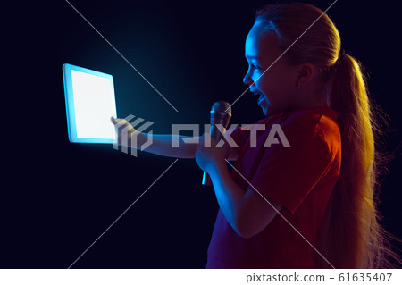 Caucasian girl's portrait isolated on dark studio background in neon light 61635407