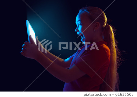 Caucasian girl's portrait isolated on dark studio background in neon light Caucasian girl's portrait isolated on dark studio background in neon light 61635503