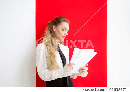 A woman in a strict office suit stands in the office and flips papers with documents 61638771